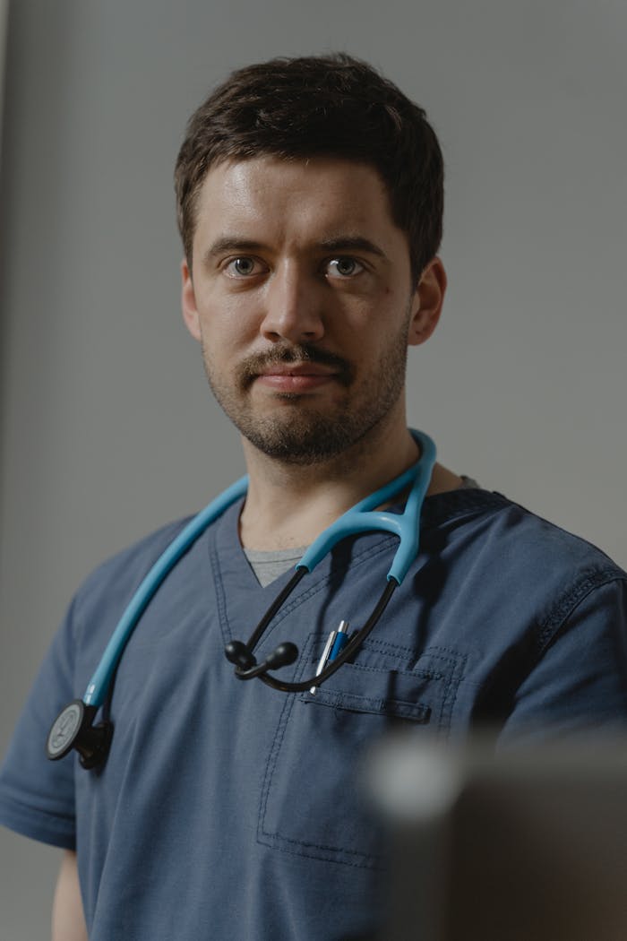 A focused portrait of a healthcare professional wearing scrubs and a stethoscope, symbolizing dedication.